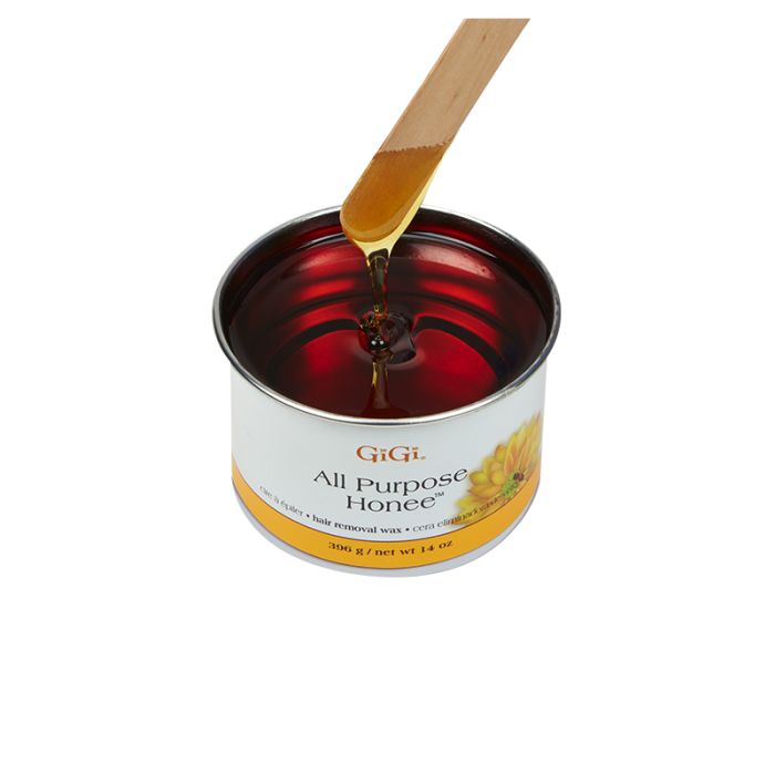Wax applicator being drawn from an open can of GiGi All Purpose Honee featuring its honey-like color and thick consistency